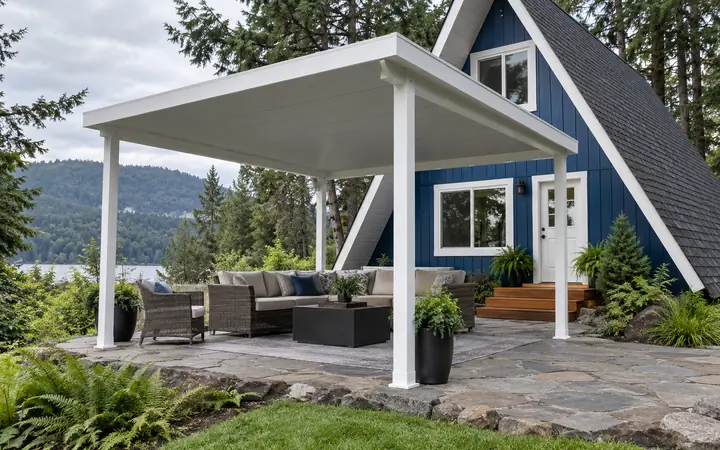 White freestanding patio cover with a solid gray roof and straight posts over a stone seating terrace.