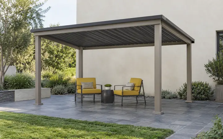 Taupe freestanding patio cover with a charcoal shed roof over slate paving and mustard-yellow chairs.