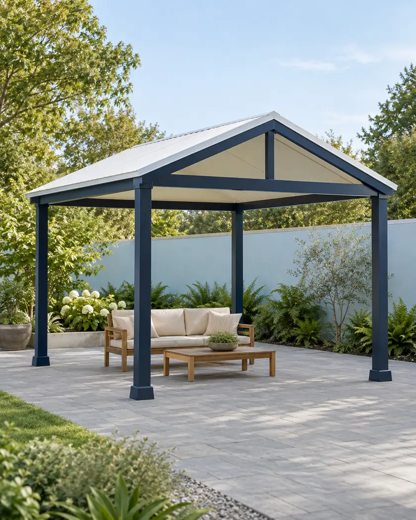 Navy freestanding patio cover with a white gable roof above gray paving and a cedar bench.