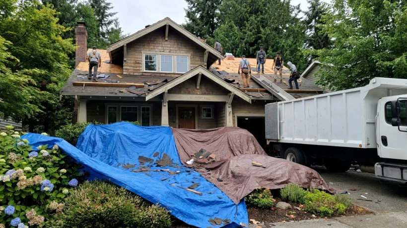 Tarps protecting the landscaping of a two-story home during a roof replacement.