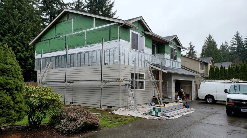 A home exterior under construction showing weather-resistant wrap and rigid foam insulation beneath new siding.